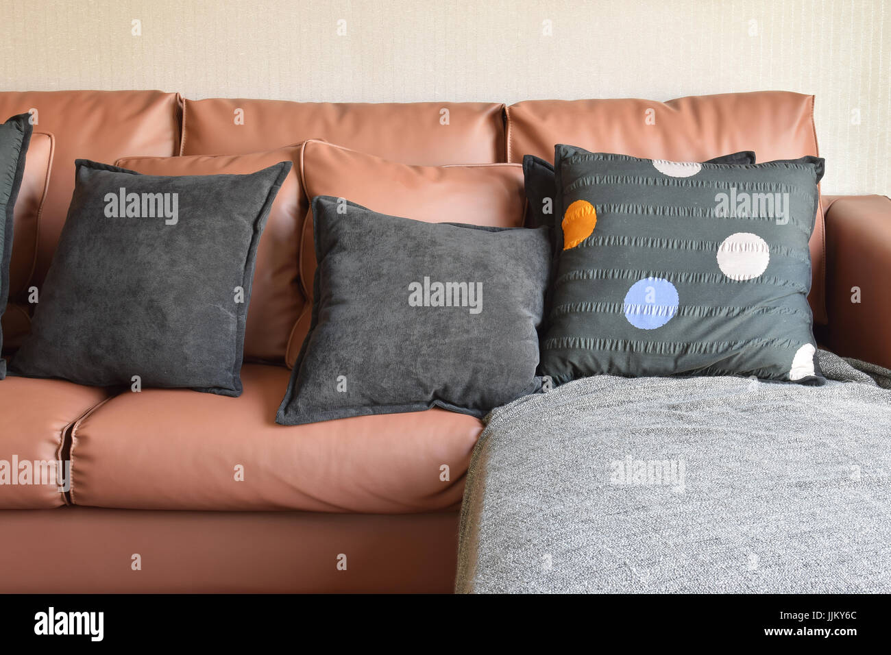 modern living room design with brown leather sofa and black pillows