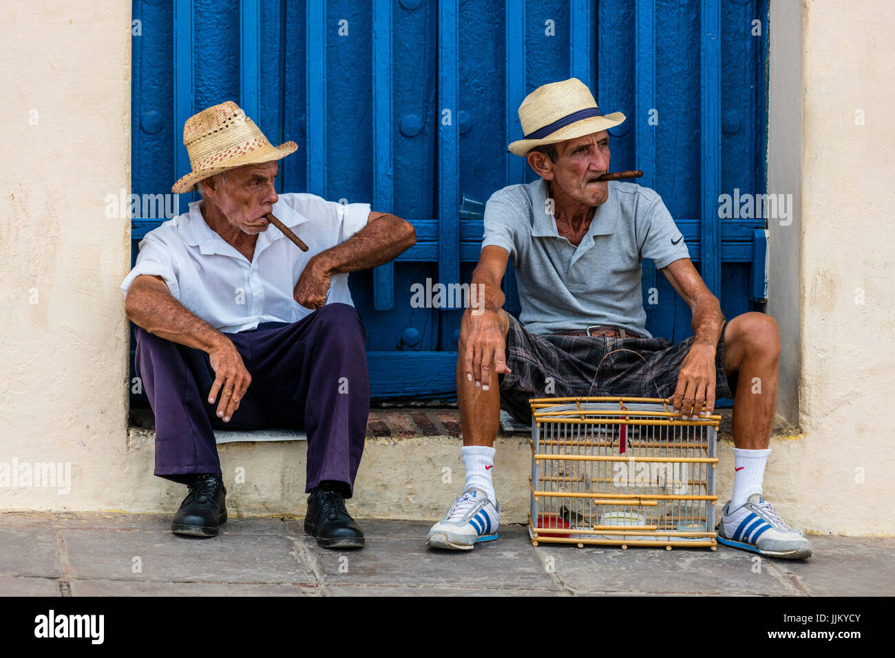 Older Cuban men smoking cigars in the PLAZA MAYOR - TRINIDAD, CUBA Stock Photo