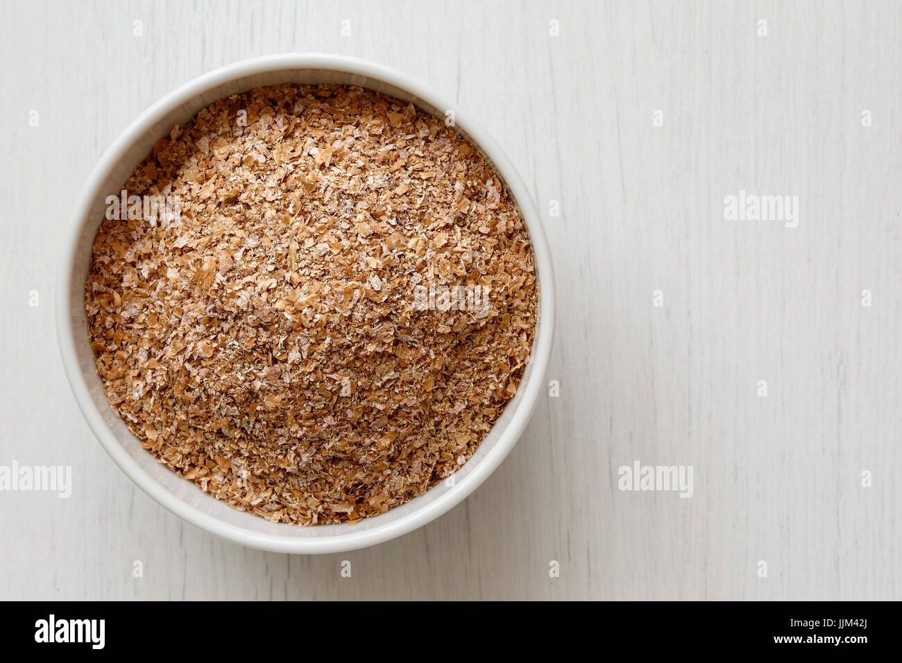 Wheat bran  in white ceramic bowl isolated on painted white wood from above. Stock Photo