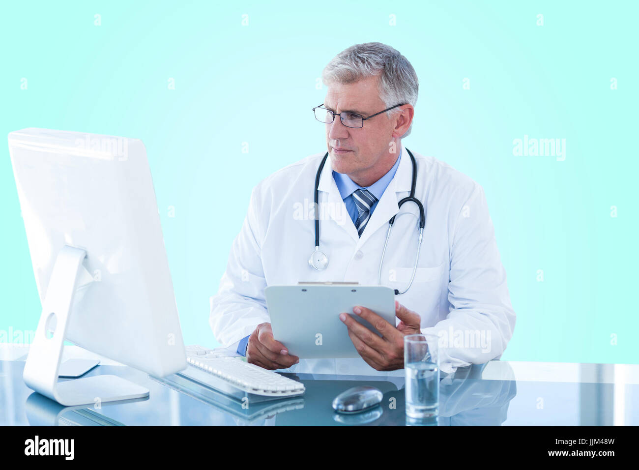 Composite 3d image of male doctor holding clipboard while looking at computer monitor Stock Photo