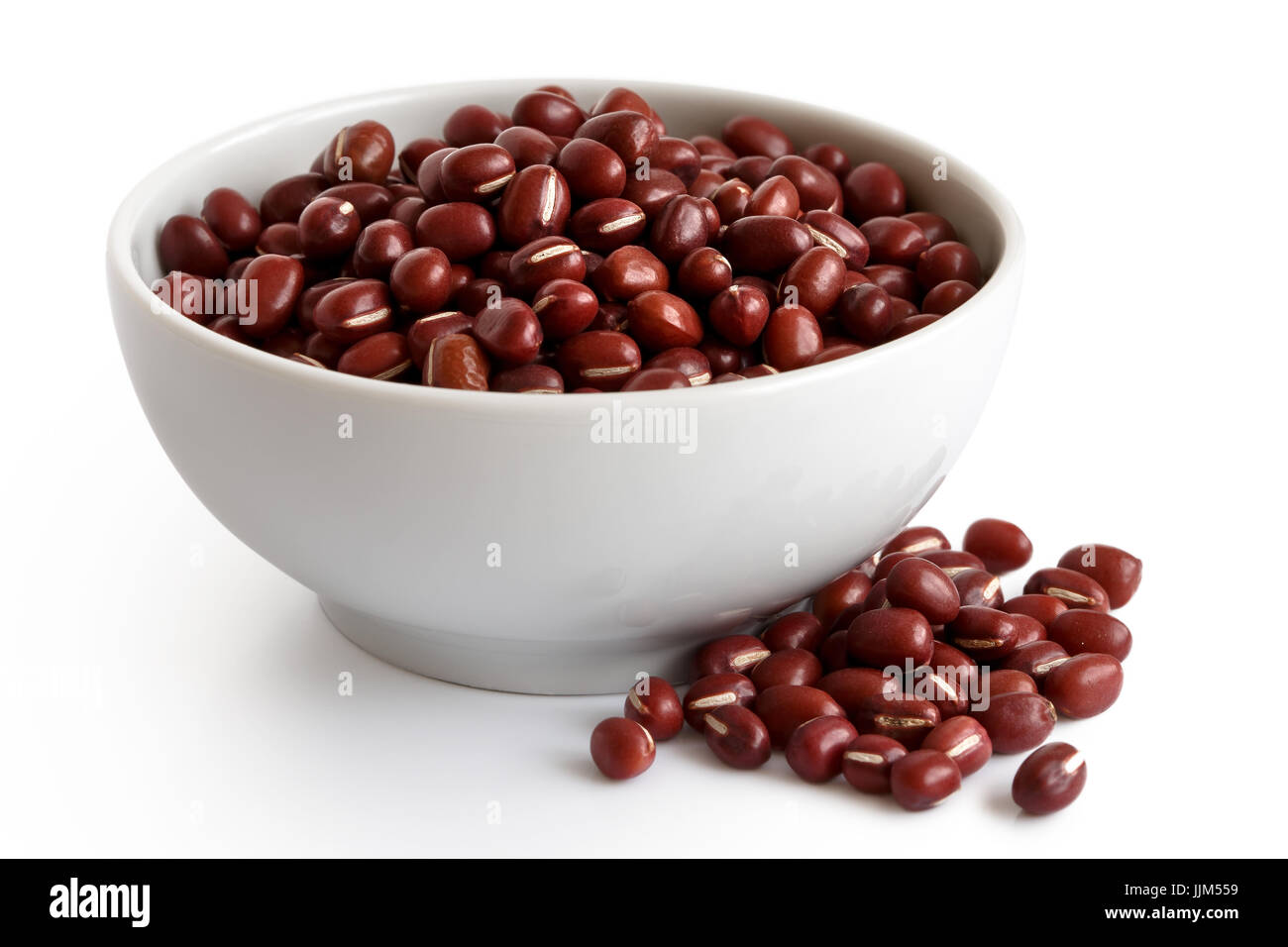 Dry adzuki beans  in white ceramic bowl isolated on white. Spilled beans. Stock Photo