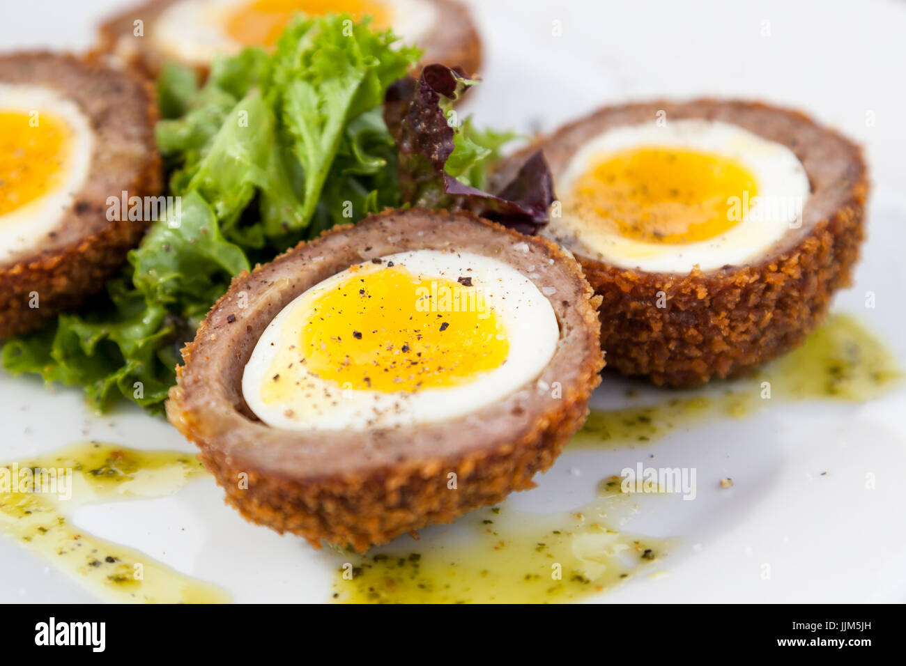 A soft yolk egg in a shell of deep fried sausage with spices and garnish Stock Photo Alamy