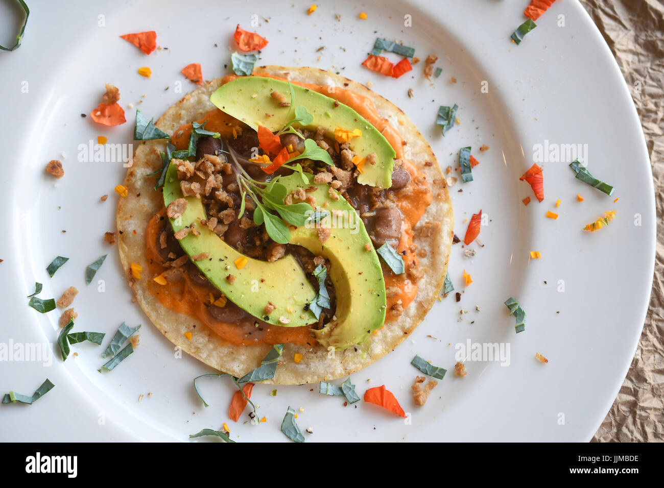 Taco Tuesday, vegan tacos with chorizo beans, vegan cheese, avocado, blue flower petal and a yellow flower. Stock Photo