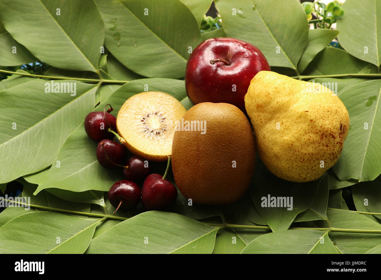 kiwifruit,apples,pear and cherries on leaves background,focus at group