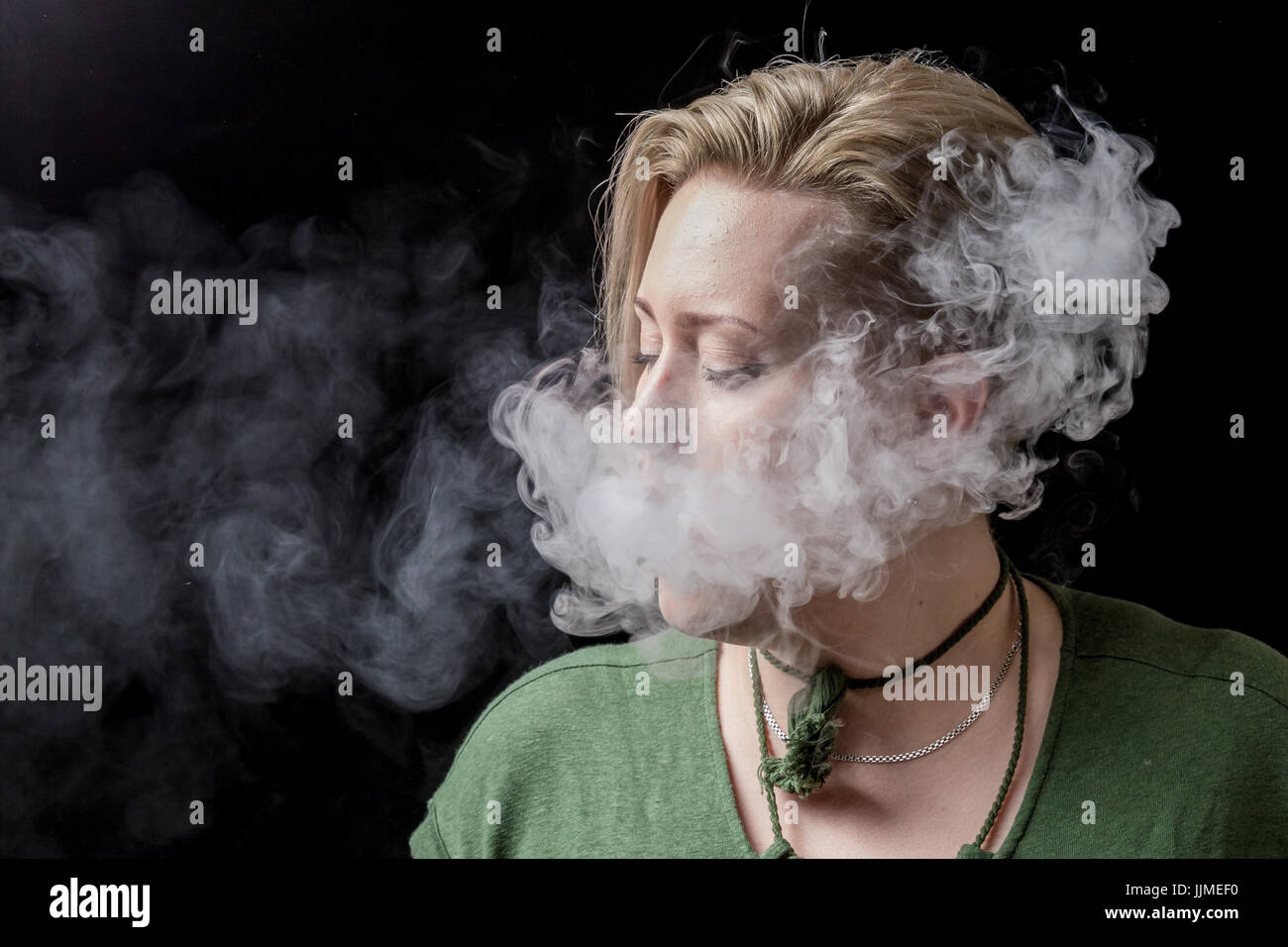 Young adult female exhaling smoke from electronic cigarette Stock Photo