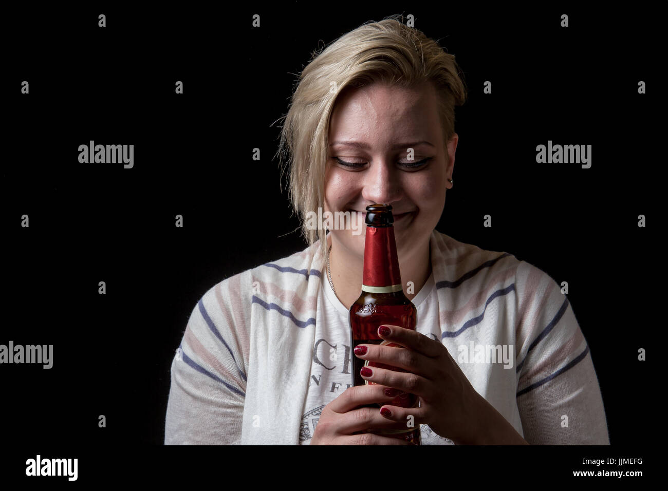 Cute female holding beer bottle and smiling Stock Photo