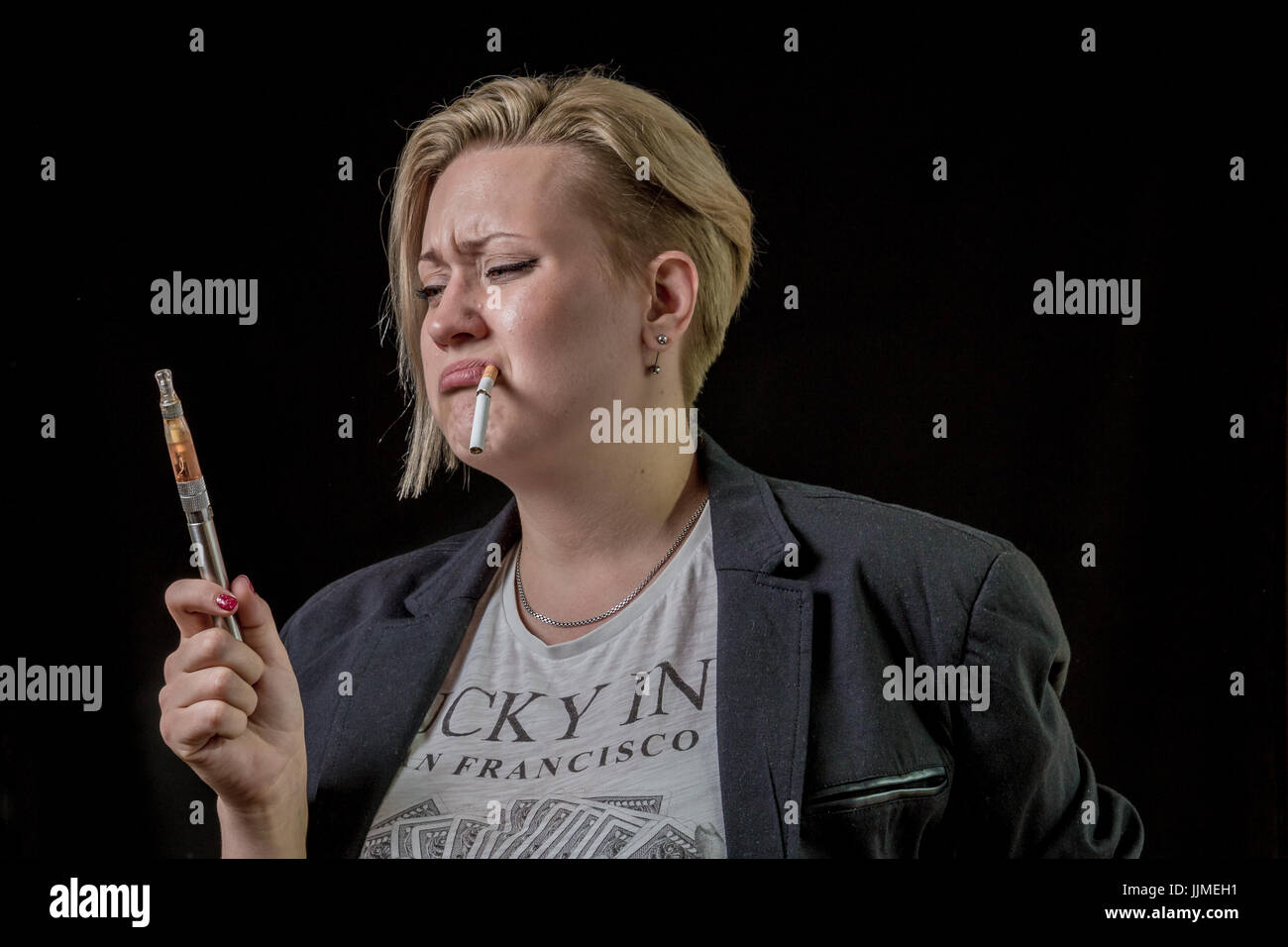 Woman looking at electronic cigarette and is doubting Stock Photo