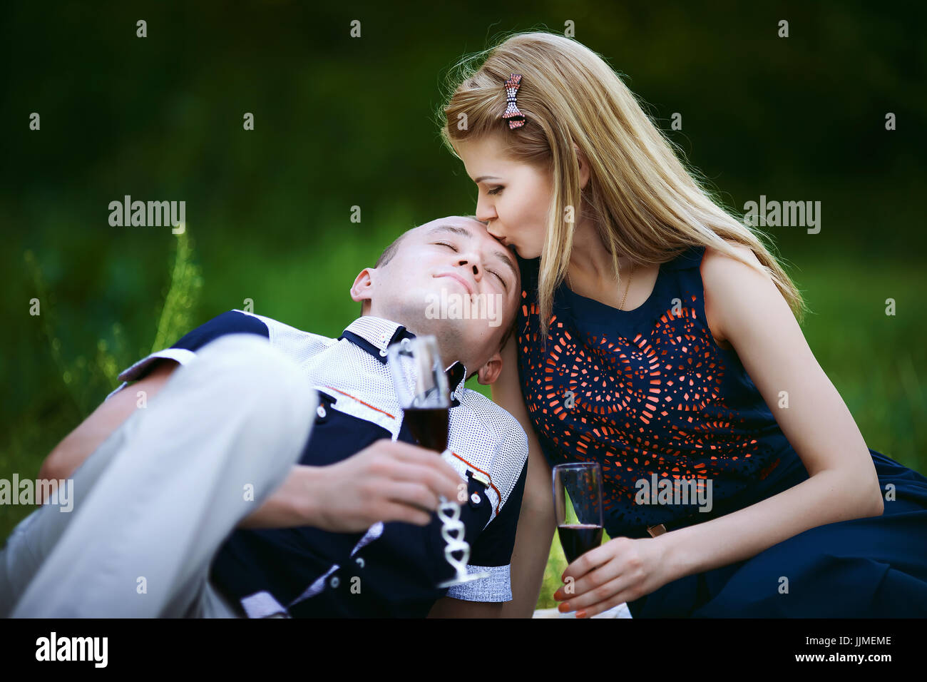 young girl kissing a man at picnic in forest. beautiful girl in dark blue  dress and man in light trousers and shirt. couple looking in each other and  Stock Photo - Alamy