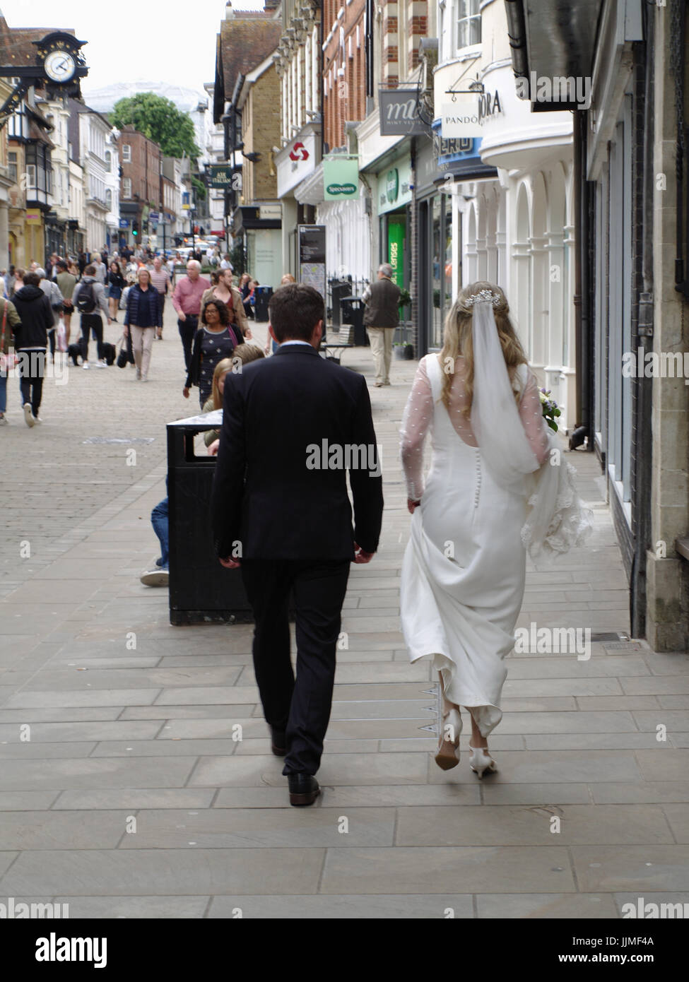 Bride & groom walking along pavement in Winchester, Hampshire, England