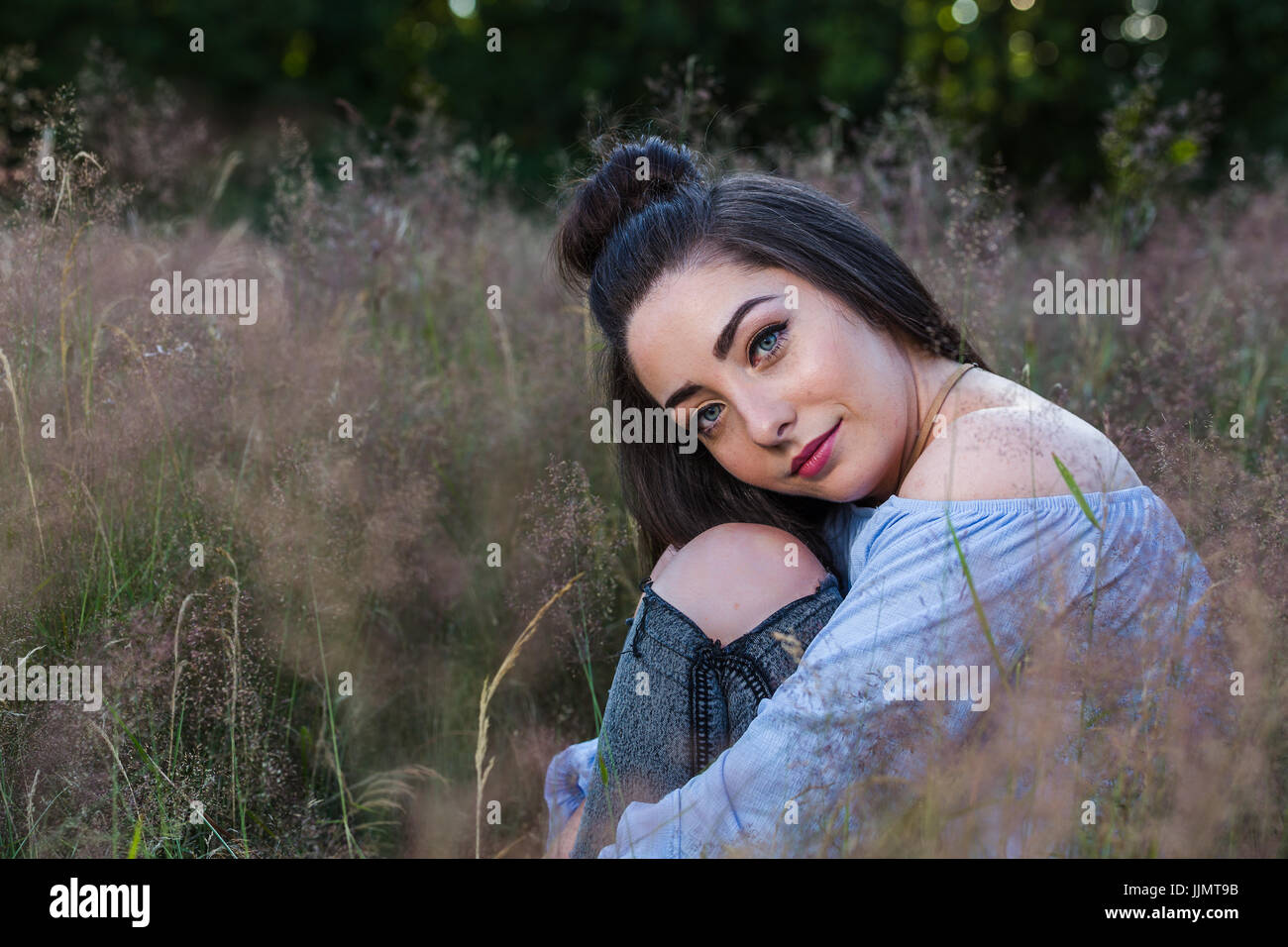 Girl sitting knees up smiling hi-res stock photography and images - Alamy