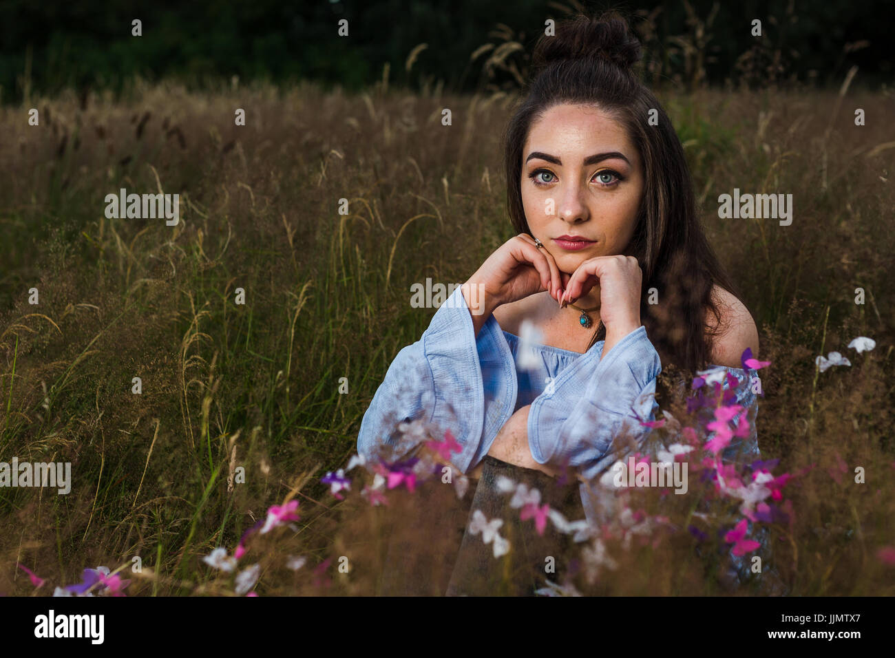 My friend gives a serious expression on her face during an outdoor potrait one summers evening in a meadow near Liverpool. Stock Photo