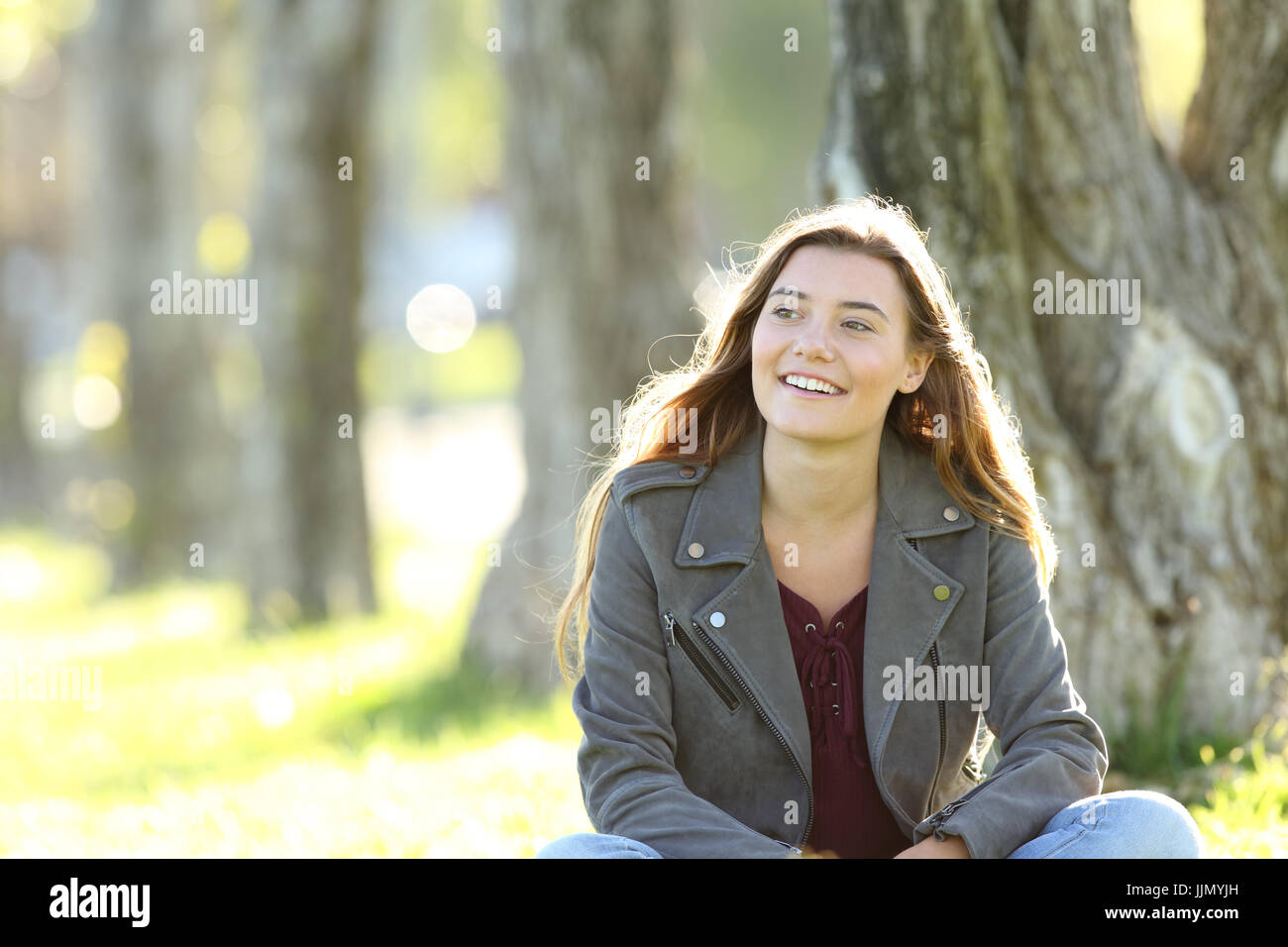 Front view of a single teen sitting and thinking looking at side outside in a park Stock Photo