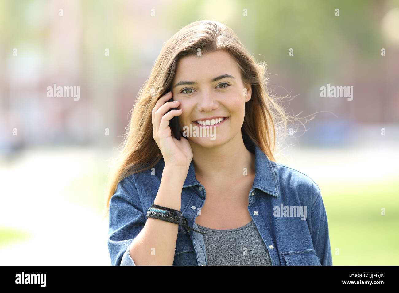 telegram pijpleiding houd er rekening mee dat Front view of a single teen girl walking towards camera and calling on  phone looking at you in the street Stock Photo - Alamy