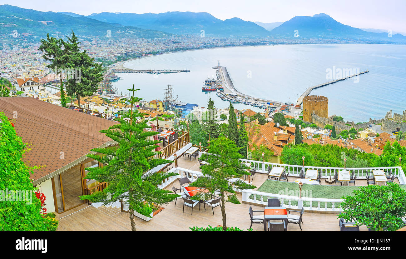 The luxury restaurant on the Castle Hill of Alanya boasts amazing summer terrace, overlooking old town, harbor, fortress walls, Red Tower, and Taurus  Stock Photo