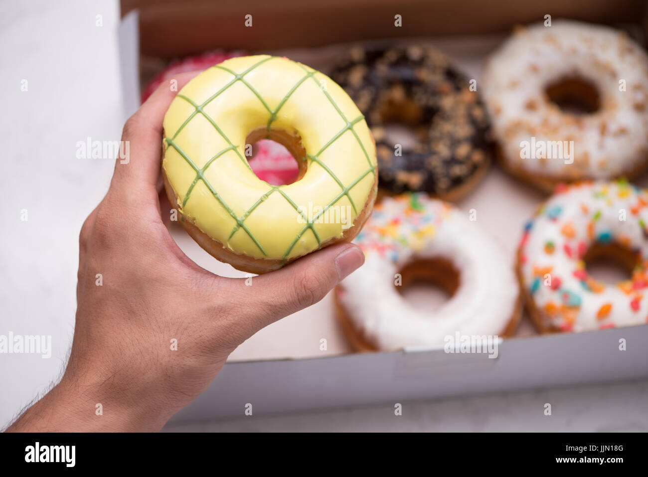 Hand holding colorful round donuts in the box Stock Photo