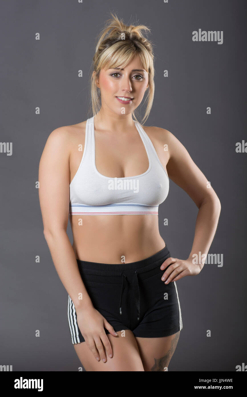 Beautiful young woman wearing sports bra and shorts hands on hips