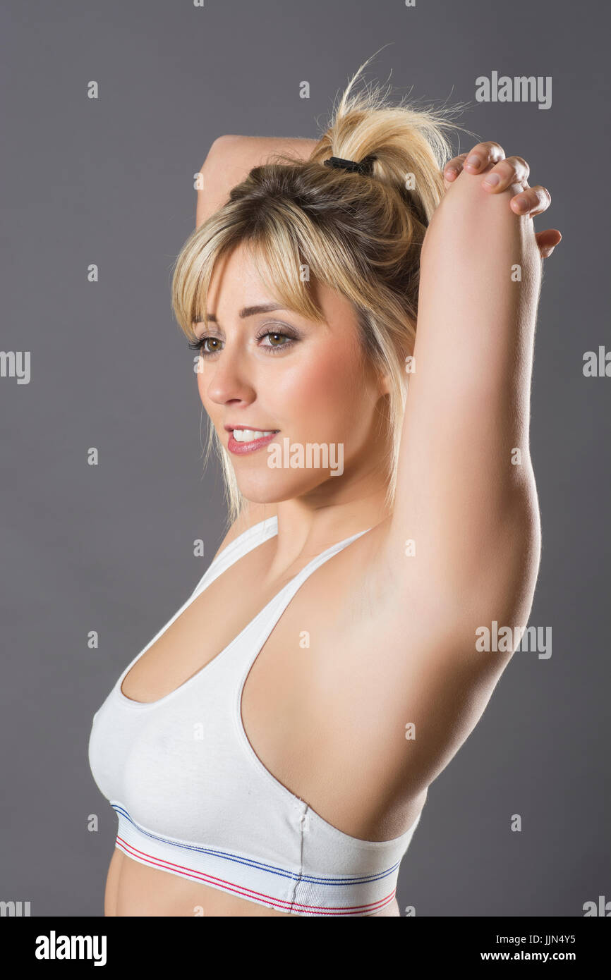 Beautiful blond woman stretching triceps arms wearing a sports bra Stock Photo