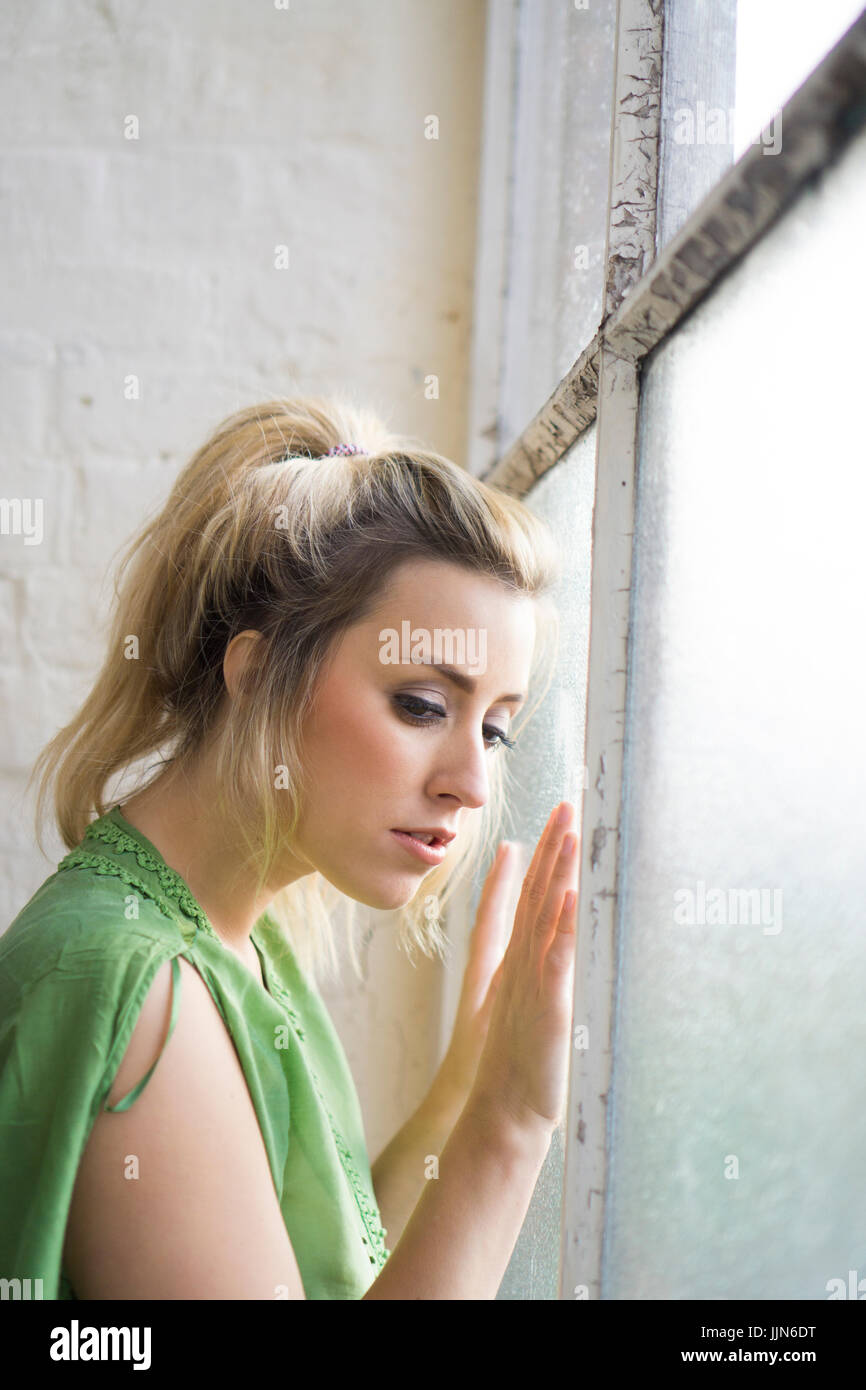 Sad young woman lookinng out of the window Stock Photo - Alamy
