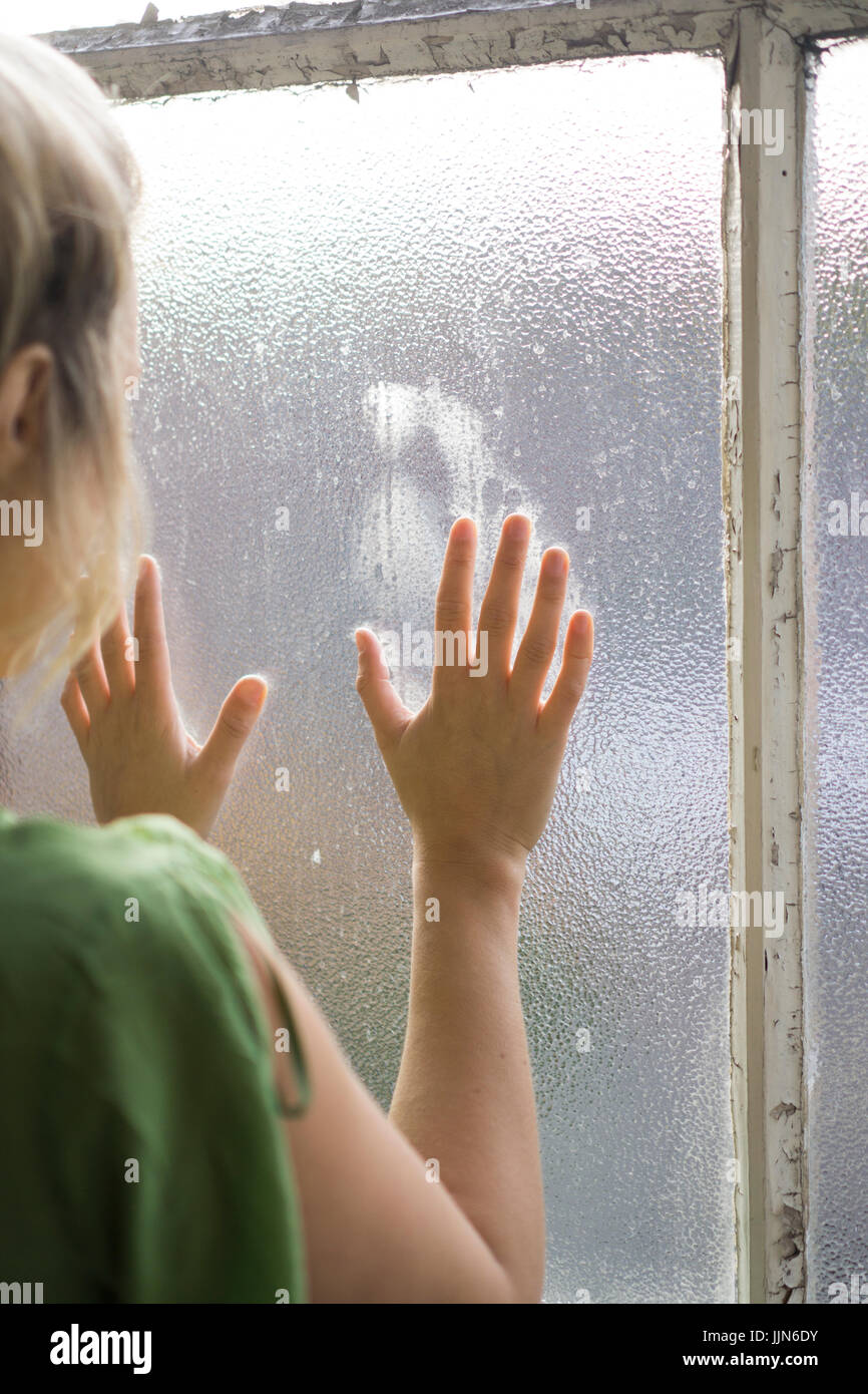 Rear view of a young blond woman standing by the window Stock Photo - Alamy