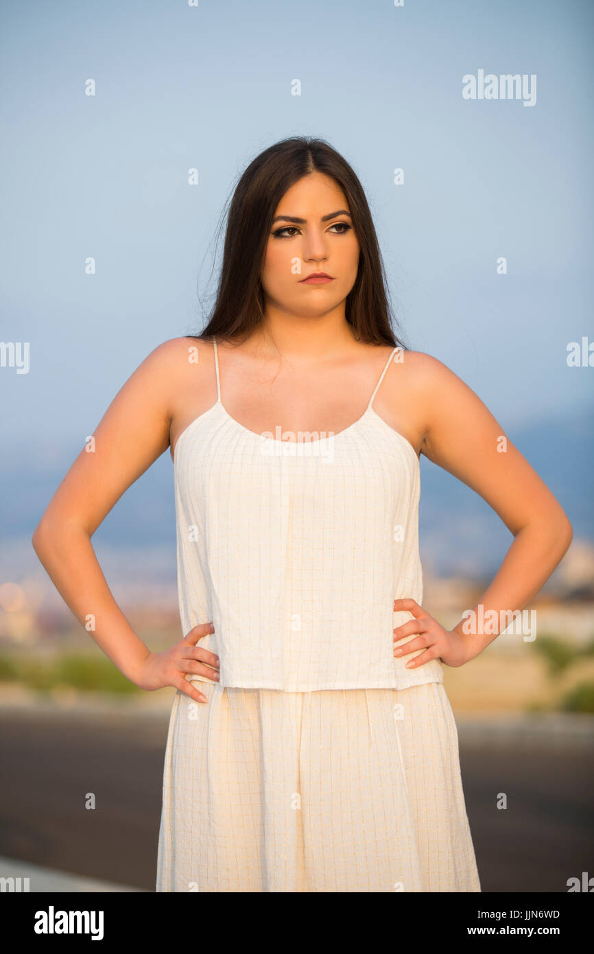 Serious young woman wearing a summer dress standing outdoors hands on ...