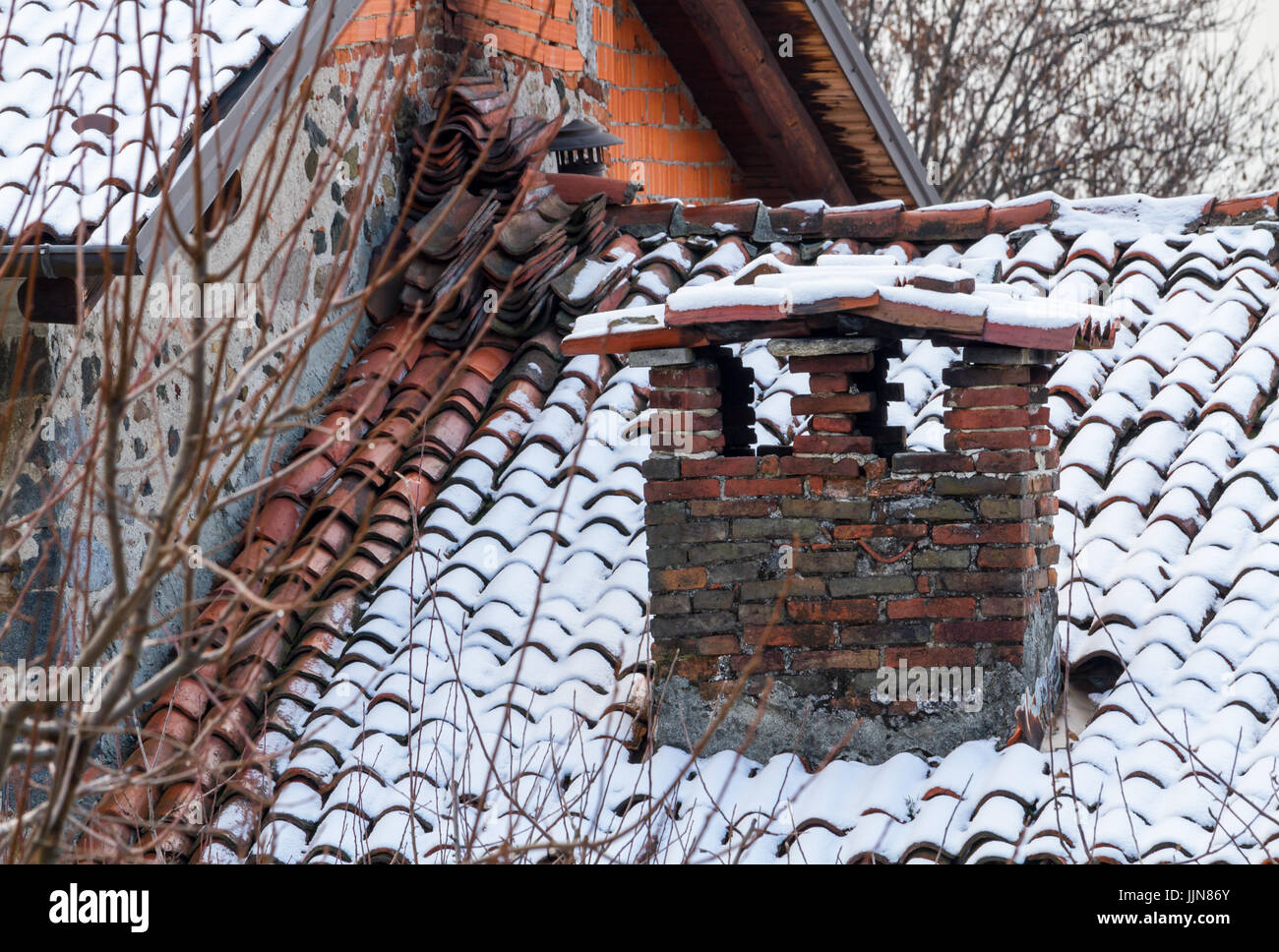 Big and old brick chimney with snow, old roof with large fireplace Stock Photo