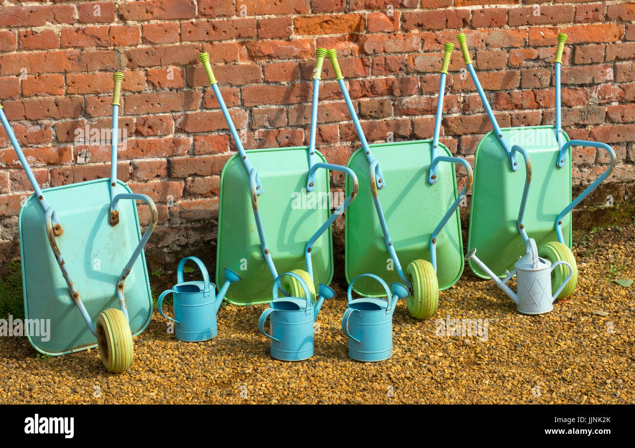 Childrens wheel barrows and watering cans in school gardening project Stock Photo