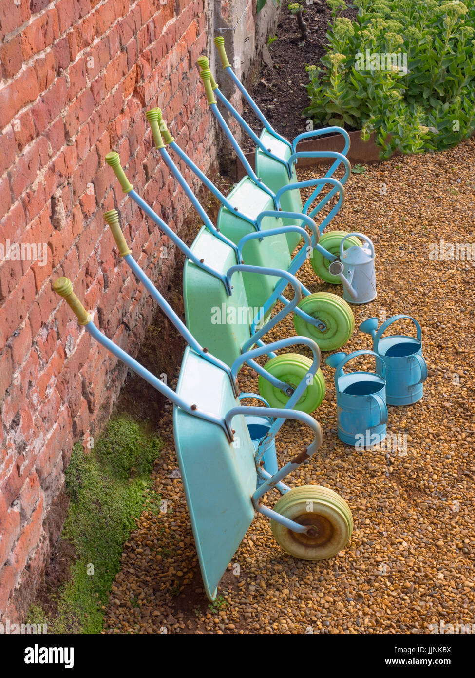 Childrens wheel barrows and watering cans in school gardening project Stock Photo