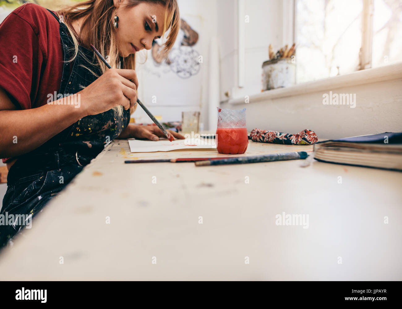 Image of beautiful woman drawing pictures in her workshop. Female artist painting in her studio. Stock Photo