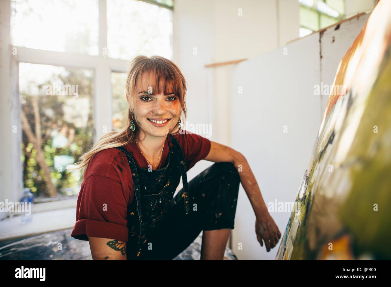 Indoor shot of professional female painter in studio. Woman artist making a painting on canvas in her workshop. Stock Photo