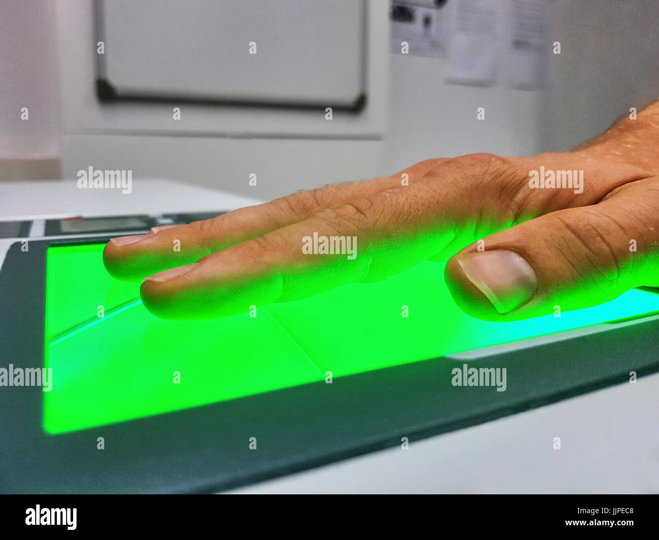 Side view from a man using a fingerprint scanner for identification. Biometrics or cybersecurity concepts. Stock Photo