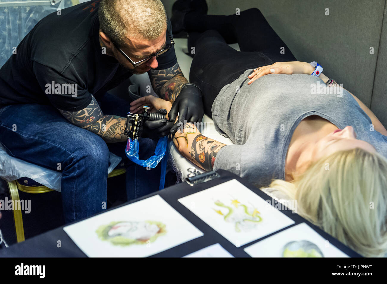 A woman being tattooed on her arm. Stock Photo