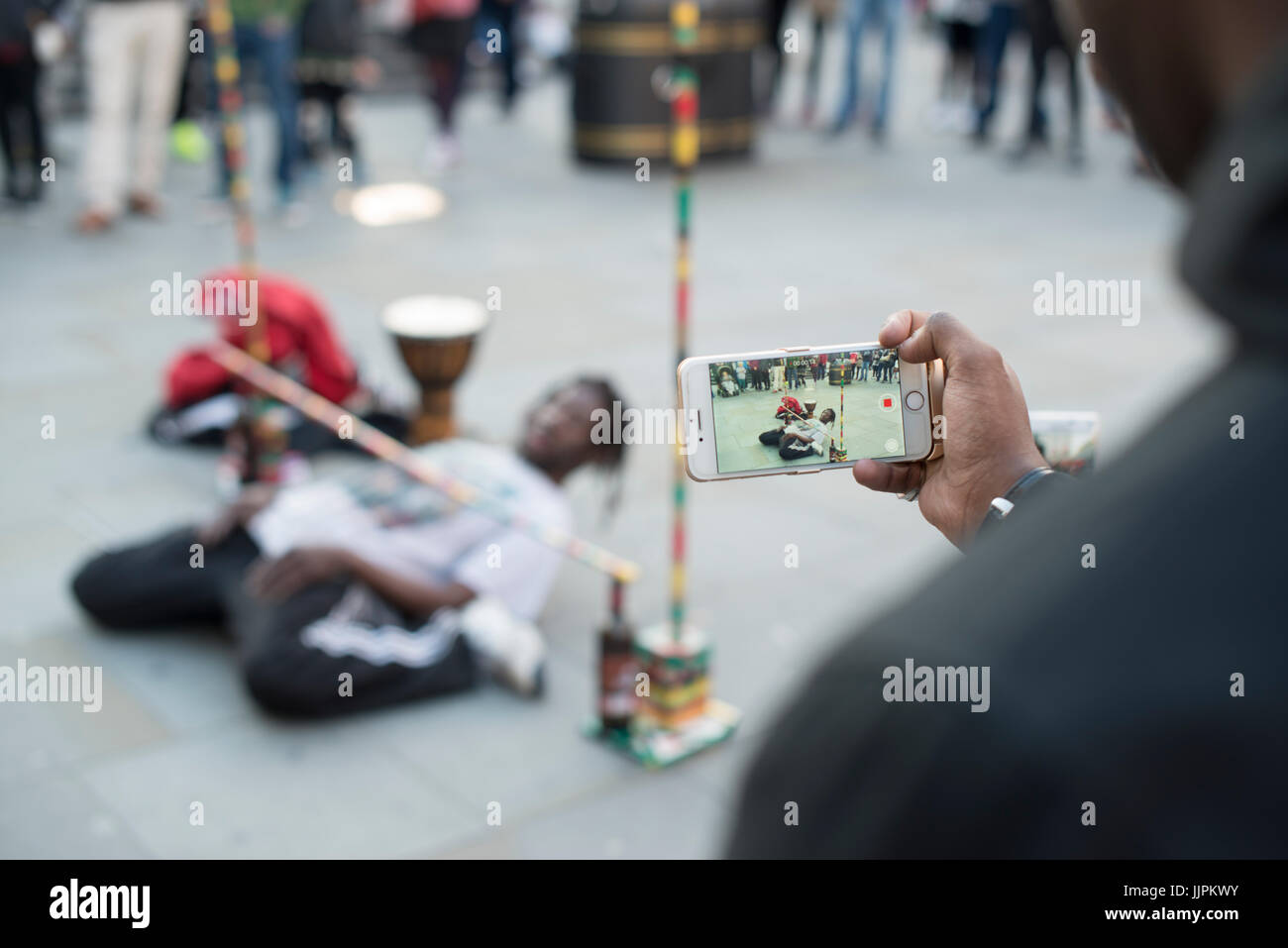 A man filming a street performer in London. Stock Photo