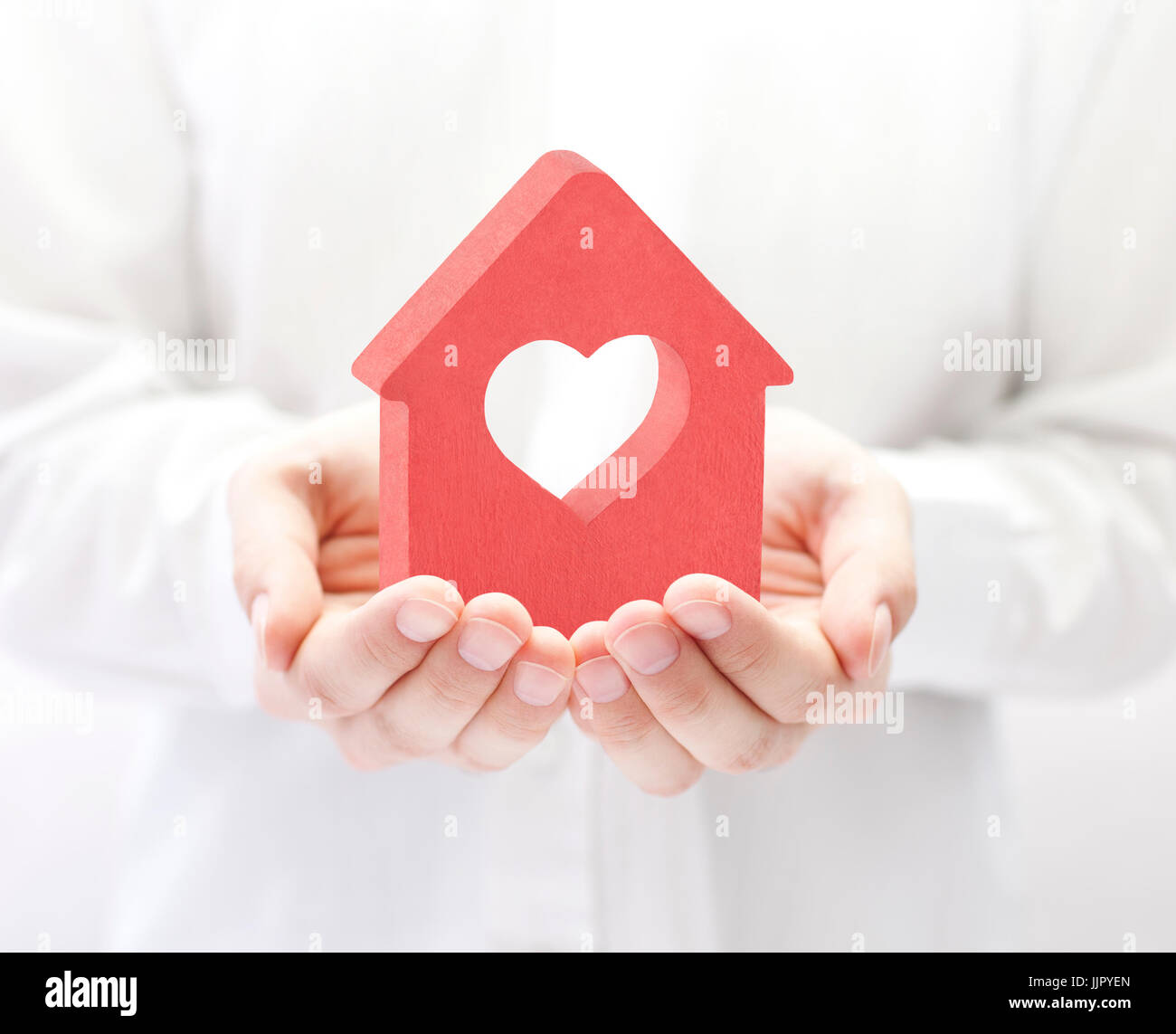 Small red house with heart in hands Stock Photo