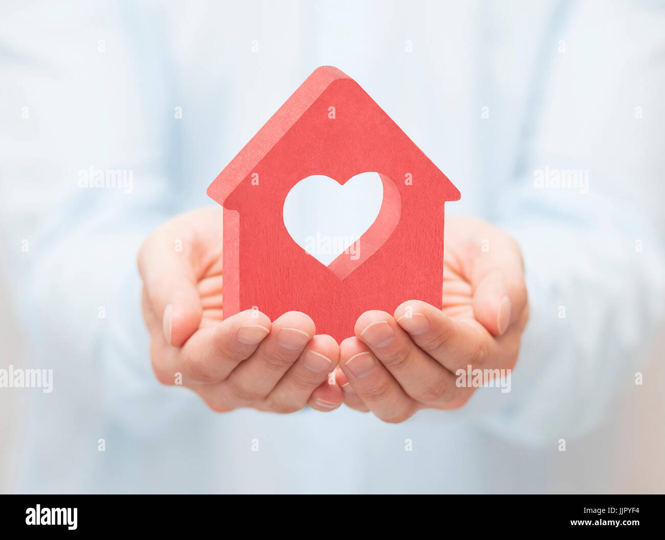 Small red house with heart in hands Stock Photo