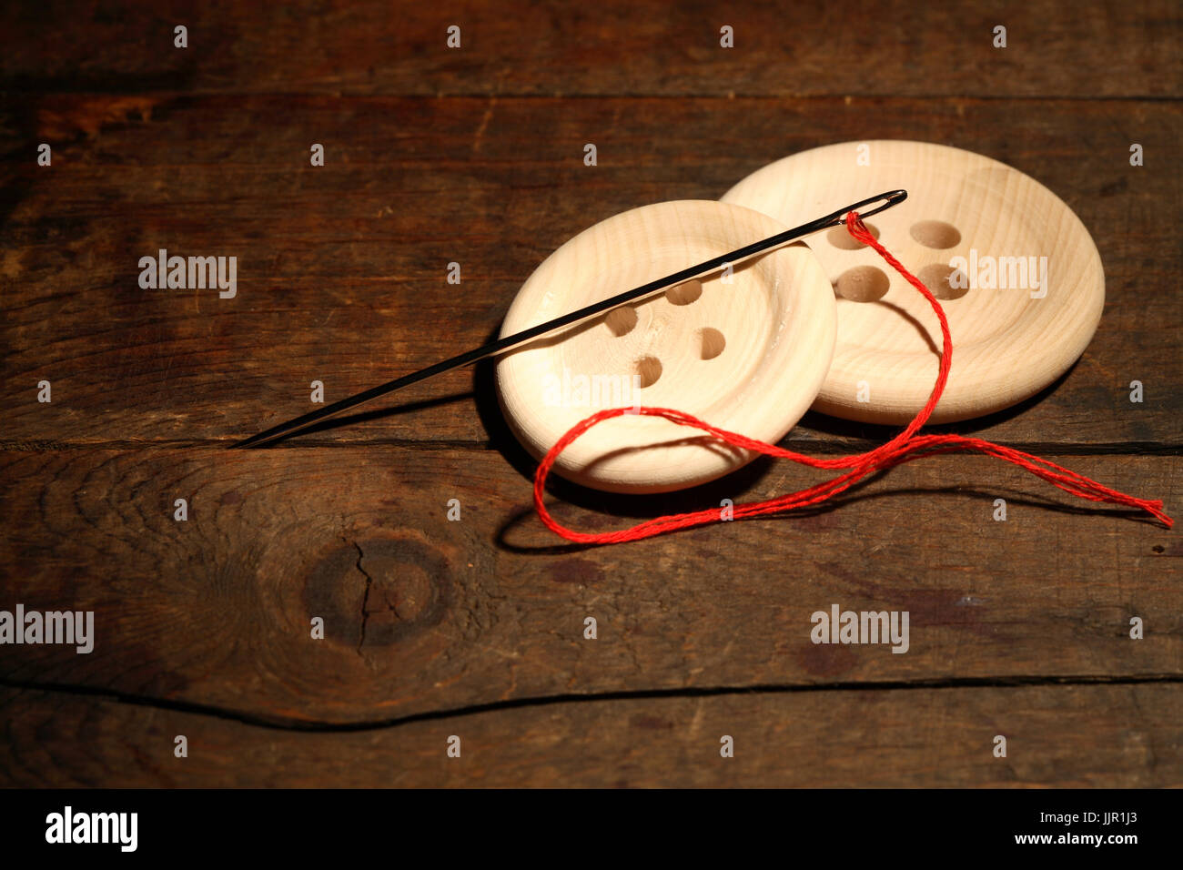 Sewing concept.Closeup of two wooden buttons and needle with thread on ...