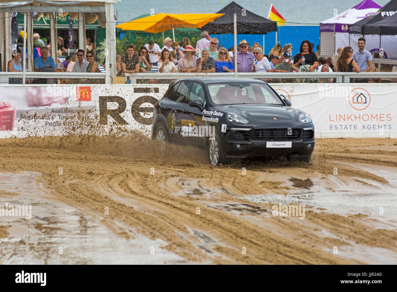 Charity race between a Porsche car and horse takes place on the beach at the British Beach Polo Championships at Sandbanks beach, Poole Dorset in July Stock Photo