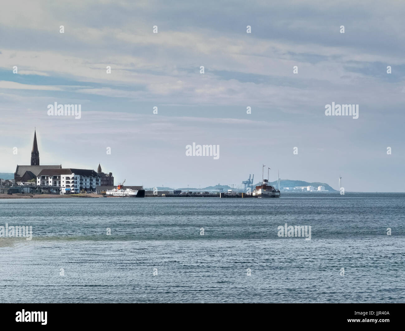 Looking south into largs towards the town centre at the paddle steamer and car ferry. Hunterston Wind turbines in the distance. Stock Photo