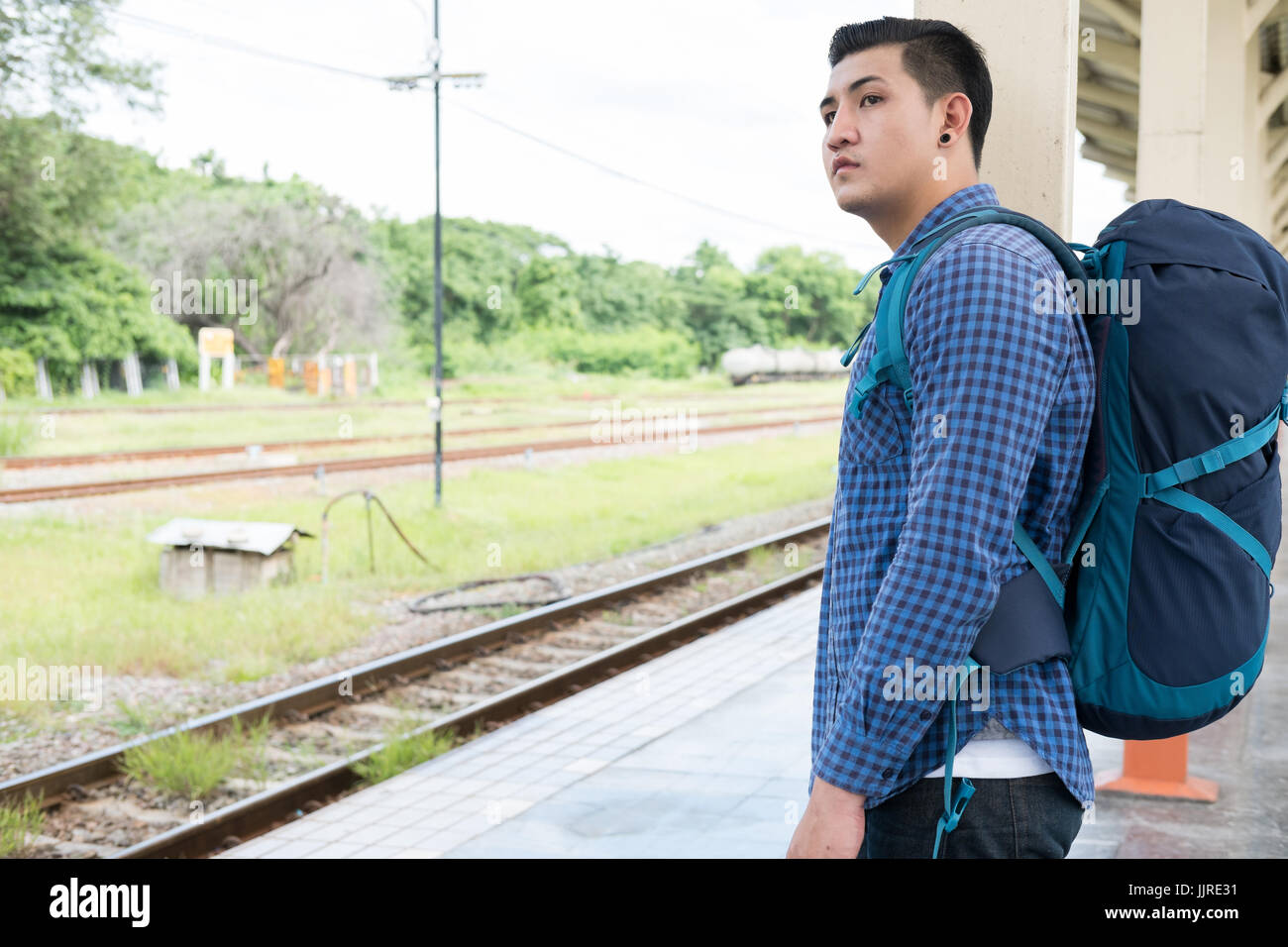 young asian man with backpack standing on platform at train station ...
