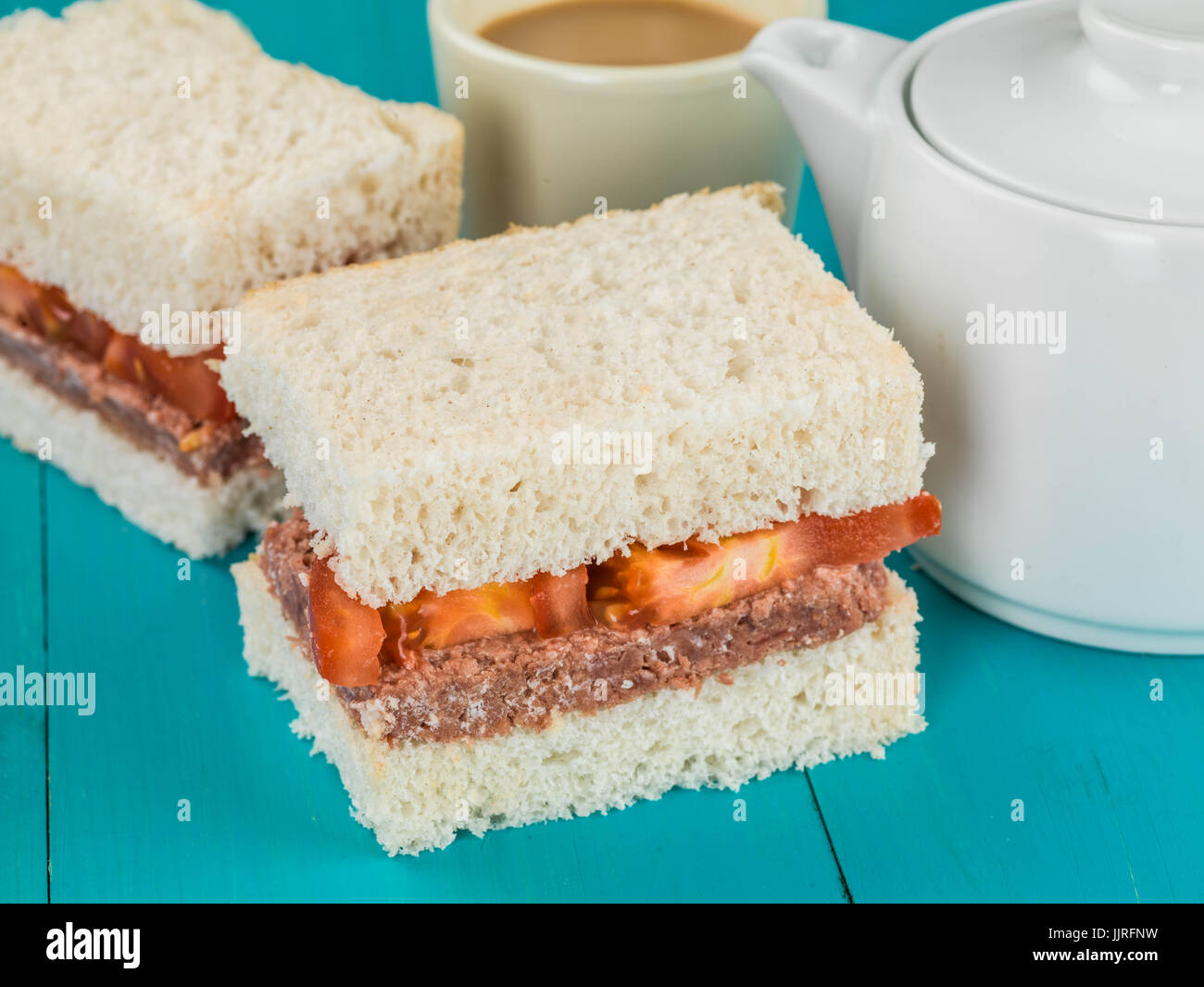 Corned Beef and Tomato White Bread Sandwich Against a Blue Background Stock Photo