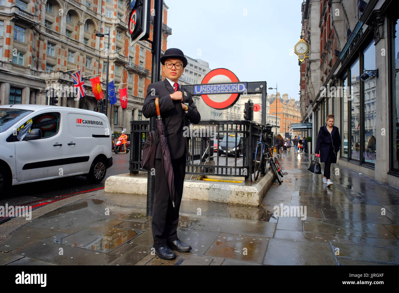 Oriental Man in Suit and bowler hat standing by undergroud station entrance in Knightsbridge, London, UK Stock Photo