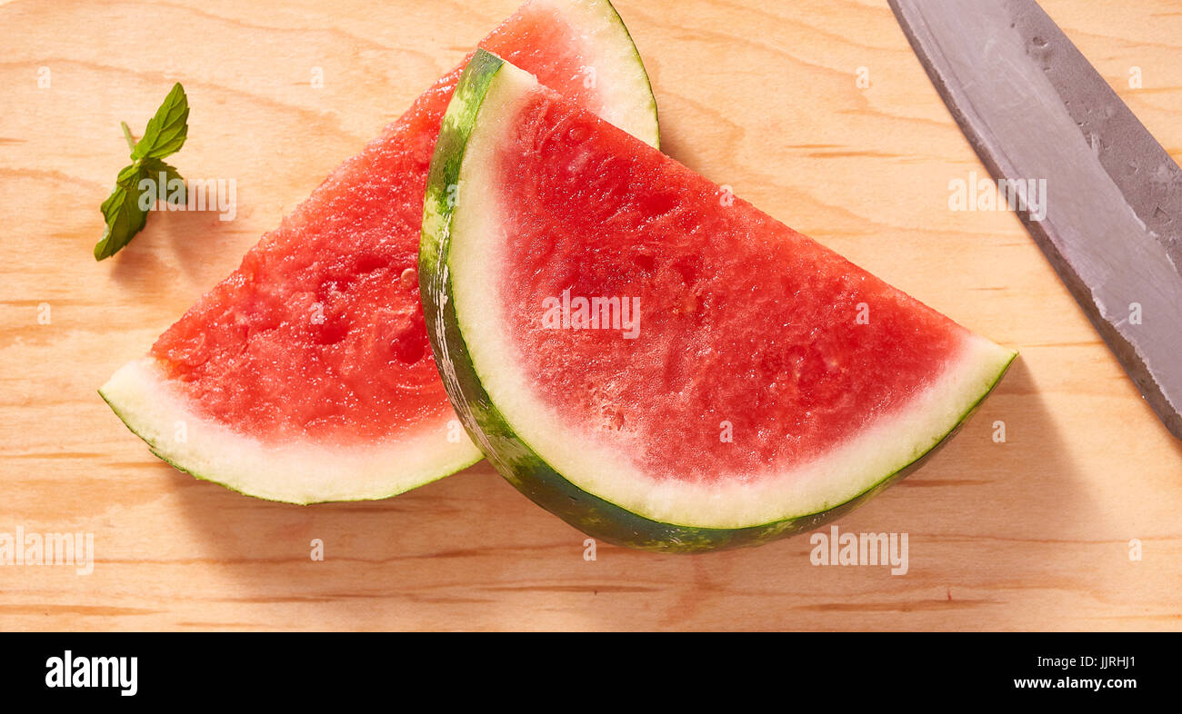 Slices of watermelon on cutting board with knife and mint Stock Photo
