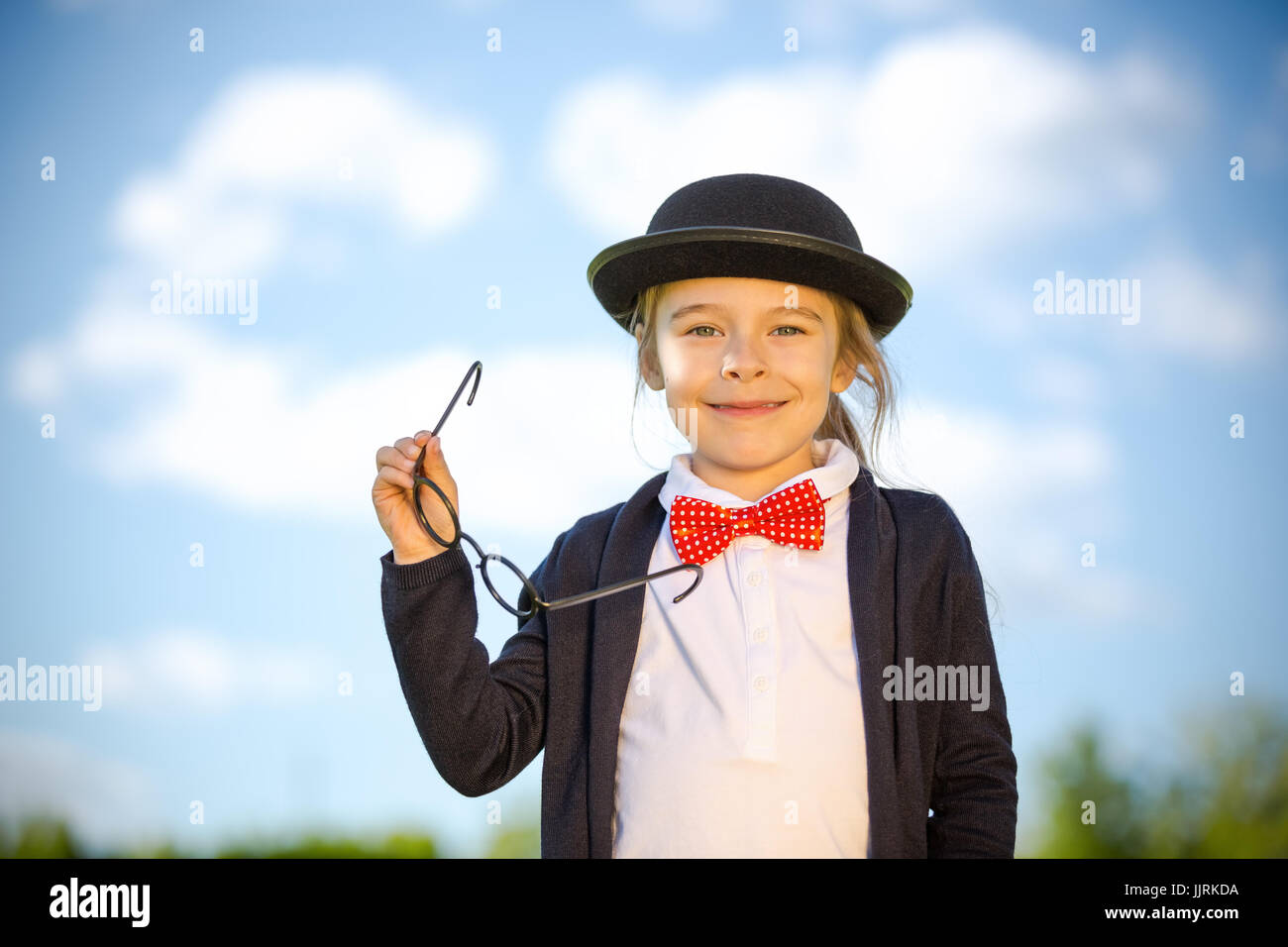 Funny little girl in bow tie and bowler hat. Stock Photo