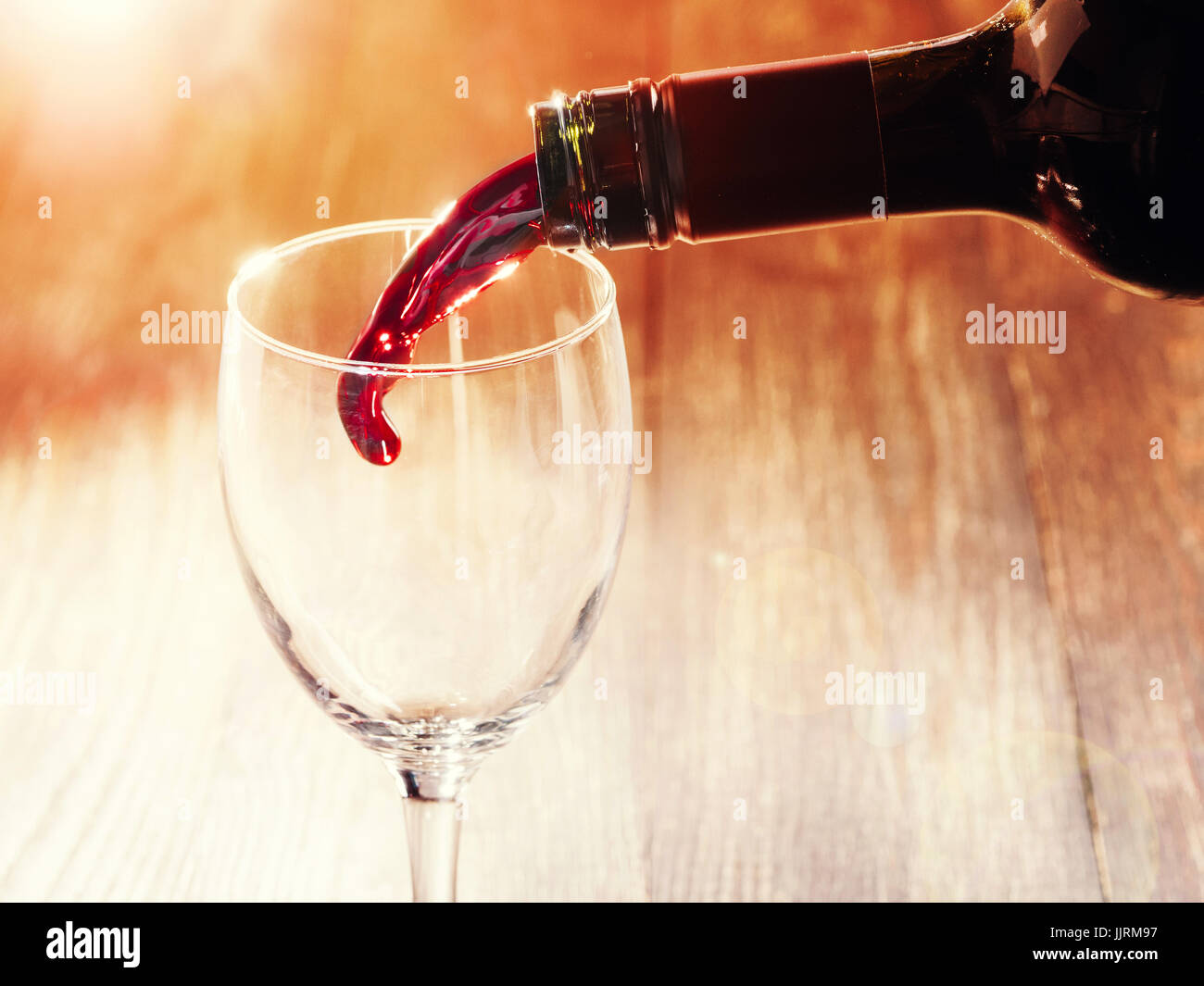 Closeup of red wine pouring in glass. Copy space. Sunflare effect Stock Photo