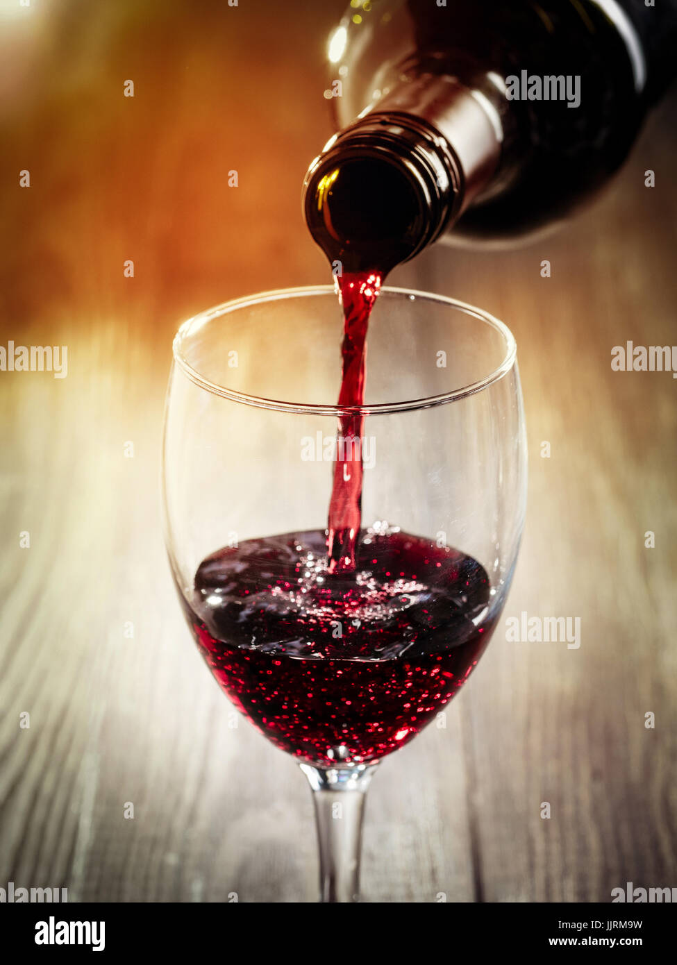Closeup of red wine pouring in glass. Copy space. Sunflare effect Stock Photo