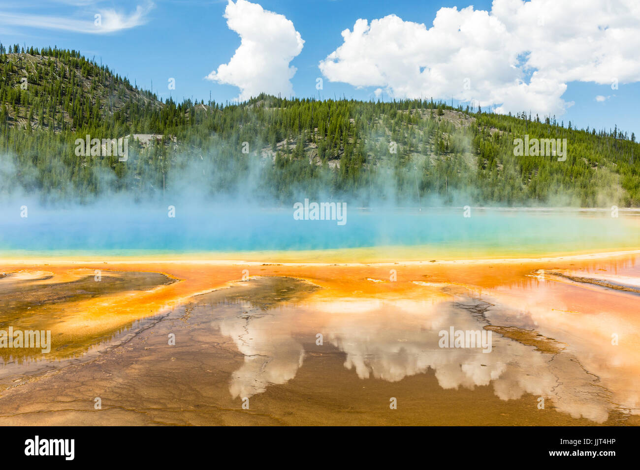 Clouds reflected in the the vivid rainbow colors of the Grand Prismatic Spring in Yellowstone National Park, Wyoming Stock Photo