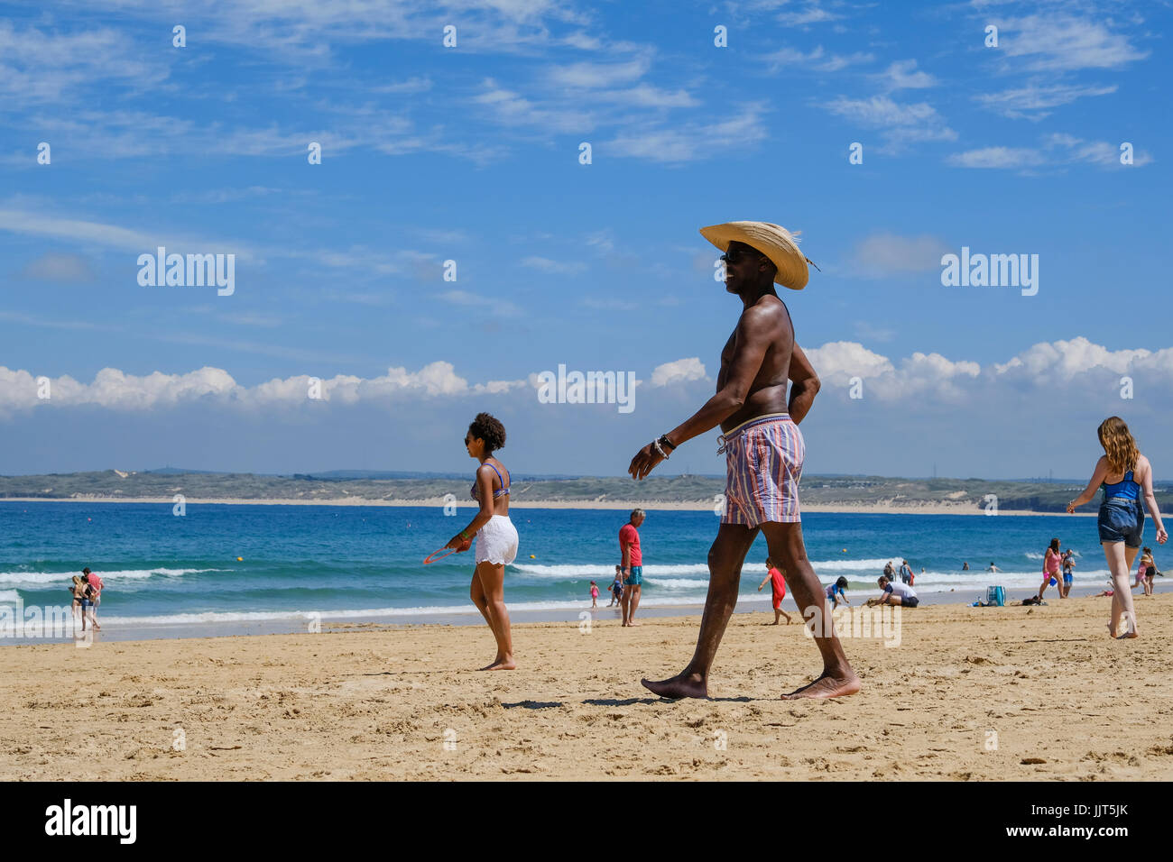 Black man in short and wearing a straw hat on the beach in St Ives, Cornwall Stock Photo