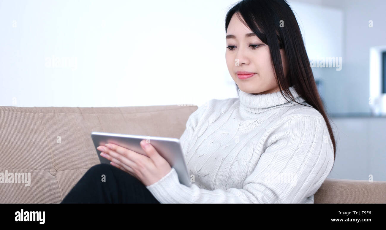 young happy asian woman sitting on sofa using Digital Tablet Stock ...