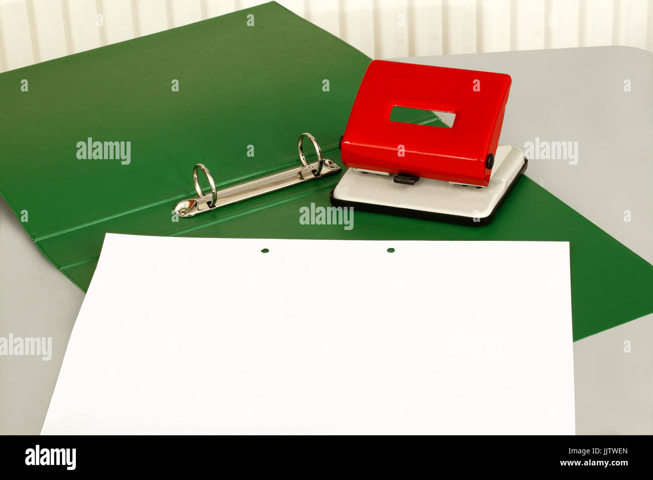 A Hole Punch Sitting On A Green Folder With A Sheet Of Plain Paper JJTWEN 