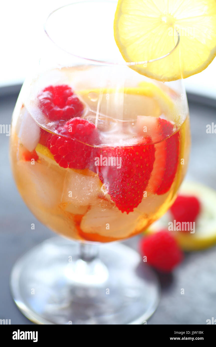 White wine with ice, lemon, strawberries and raspberries Stock Photo