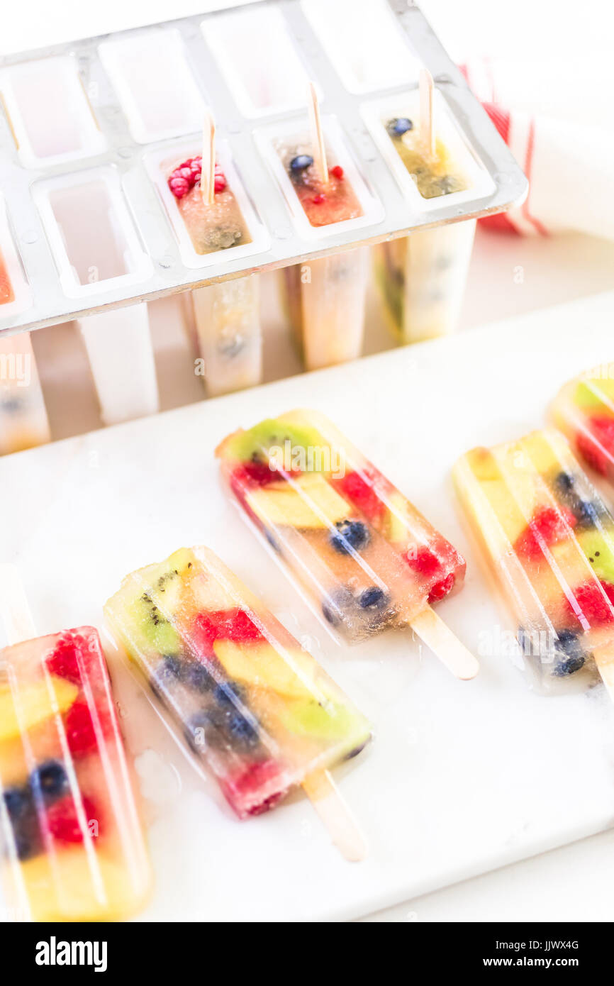 Making homemade fresh fruit popsicles with apple juice in frozn ice pop